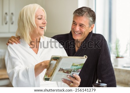Mature couple reading magazine together in morning at home in the kitchen