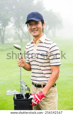 Happy golfer taking club from golf bag at the golf course