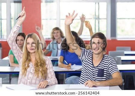 View of students raising hands in classroom
