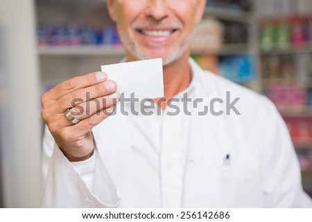 Senior pharmacist holding calling card in the pharmacy