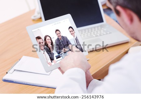Doctors using laptop and digital tablet in meeting against portrait of a positive team sitting at a table