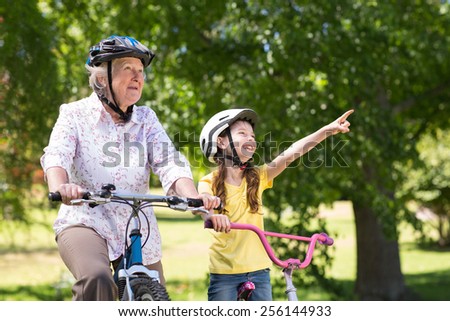 Happy grandmother with her granddaughter on their bike on a sunny day