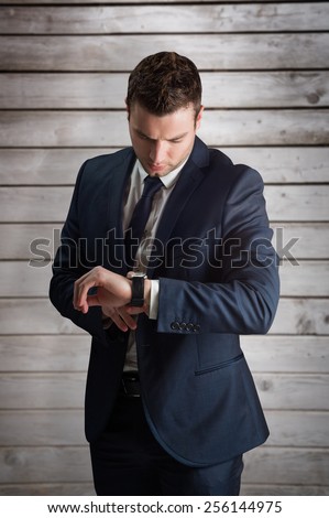 Handsome businessman checking the time against wooden planks