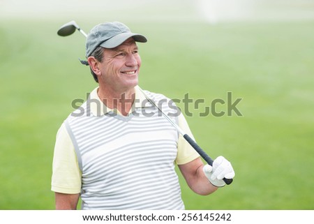 Golfer standing and swinging his club smiling at camera on a foggy day at the golf course
