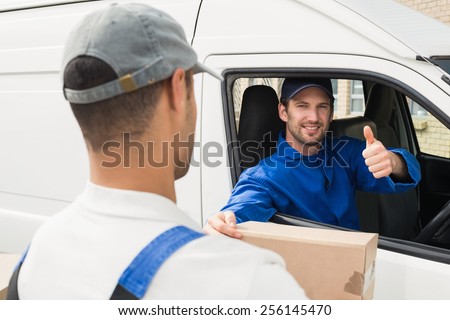 Delivery driver handing parcel to customer in his van outside the warehouse