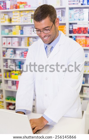 Handsome pharmacist using the computer at the hospital pharmacy