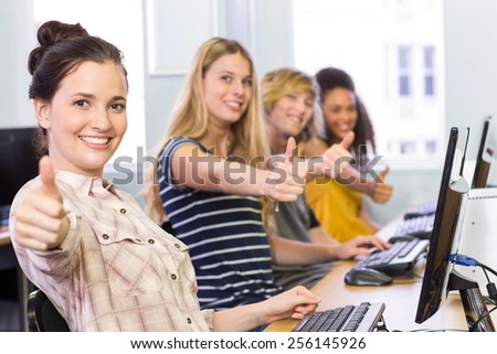 Portrait of students gesturing thumbs up in computer class