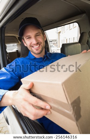 Delivery driver holding parcel in his van outside the warehouse
