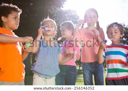 Little friends blowing bubbles in park on a sunny day