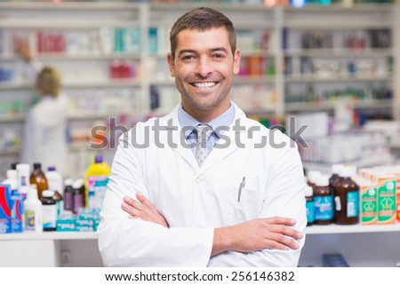 Smiling pharmacist in lab coat looking at camera in the pharmacy