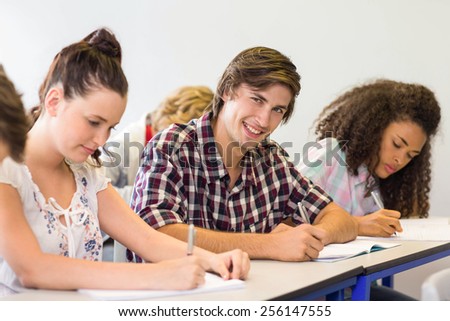 Side view of students writing notes in classroom