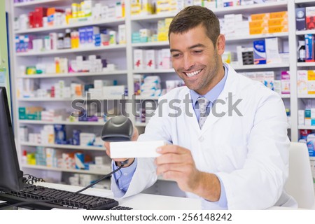 Handsome pharmacist scanning medicine box at the hospital pharmacy