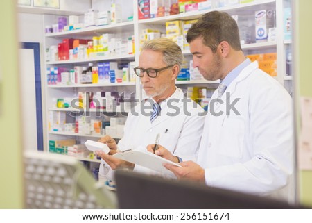 Team of pharmacists writing on clipboard in the pharmacy