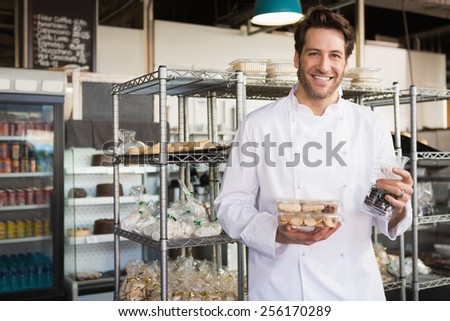 Cheerful baker holding coffee house and food at the bakery