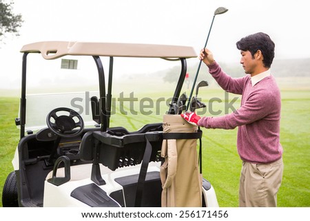 Golfer taking club in golf bag in golf course