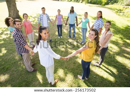 Happy friends in the park holding hands on a sunny day