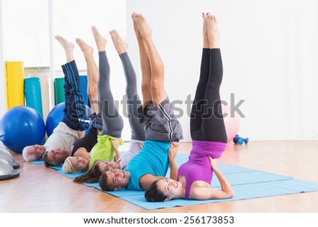 Full length portrait of happy men and women doing Pilates exercises in gym