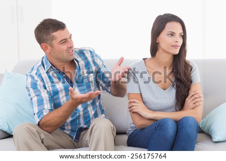 Man arguing with angry woman while sitting on sofa at home