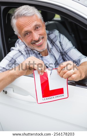 Driver smiling and tearing l plate in his car