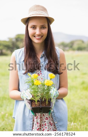 Happy woman holding potted flowers on a sunny day