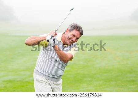 Golfer swinging his club on the course on a foggy day at the golf course