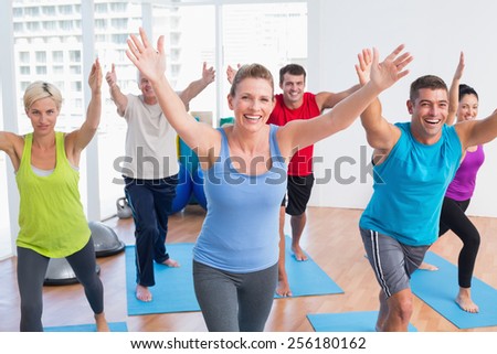 Happy fit men and women exercising in gym class