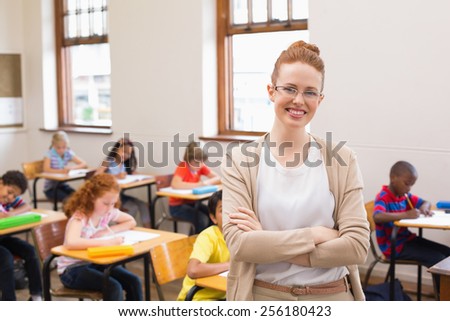Pretty teacher smiling at camera at top of classroom at the elementary school