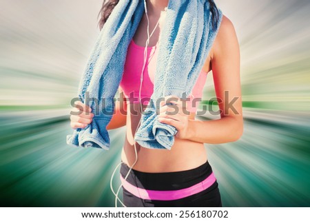 Mid section of healthy woman with towel around neck on beach against abstract background