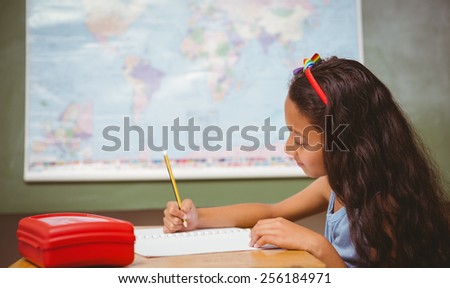 Side view of cute little girl writing book in classroom