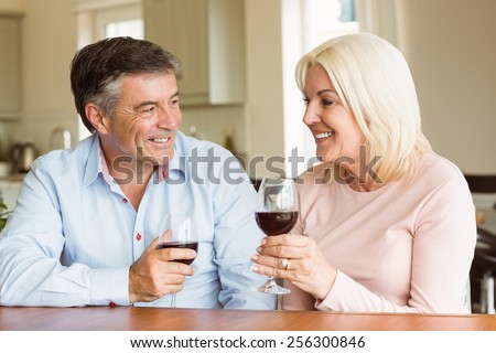 Happy mature couple drinking red wine at home in the kitchen