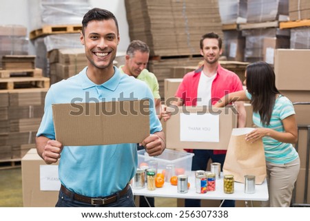 Smiling volunteer showing a poster in a large warehouse