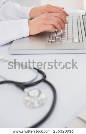 Doctor using laptop near stethoscope in medical office
