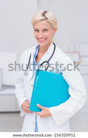 Portrait of confident female doctor holding file in clinc
