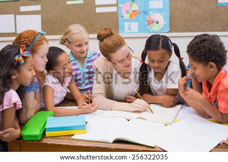 Teacher and pupils working at desk together at the elementary school