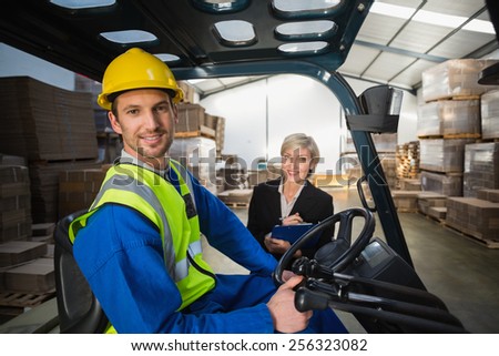 Warehouse worker and his manager smiling at camera in a large warehouse