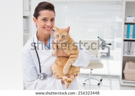 Smiling veterinarian with a cute cat in her arms in medical office