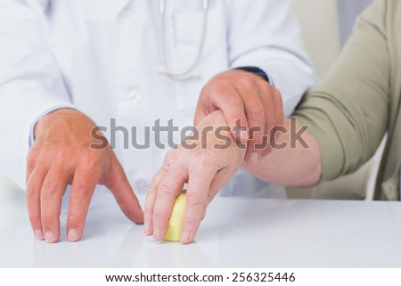 Cropped image of male doctor assisting female patient to hold weight at table in clinic