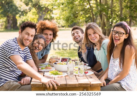 Happy friends in the park having lunch on a sunny day