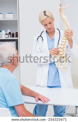Female doctor explaning spine model to senior male patient in hospital