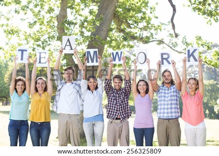 Friends holding teamwork signs in the park on a sunny day