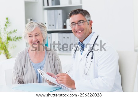 Portrait of happy male doctor and female patient in clinic
