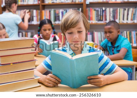 Cute pupils reading in library at the elementary school