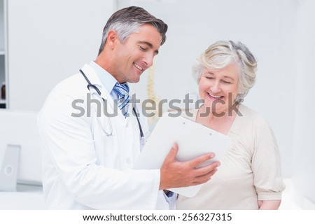 Happy doctor and patient discussing over reports in clinic