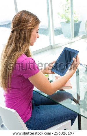Side view of beautiful casual young woman using digital tablet