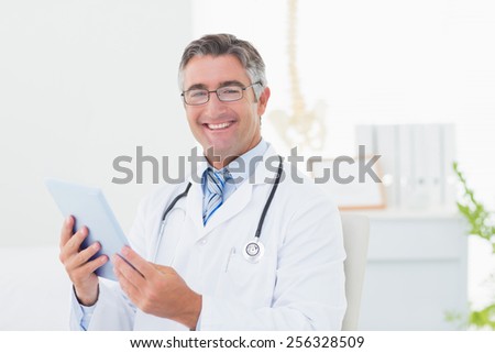 Portrait of confident male doctor using tablet computer in clinic