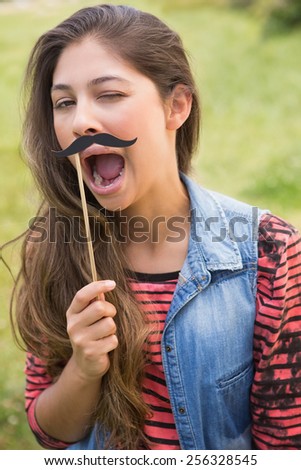 Pretty brunette with fake mustache on a sunny day