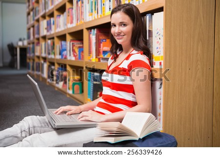 Student sitting on floor in library using laptop at the university