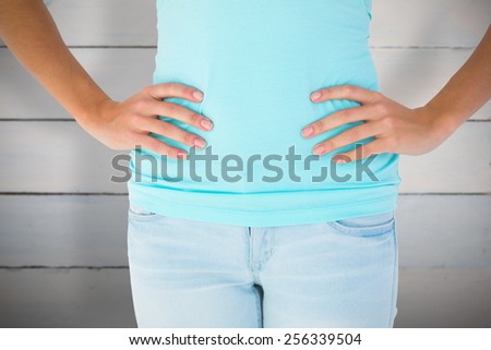 Slim woman with hands on hips against painted blue wooden planks