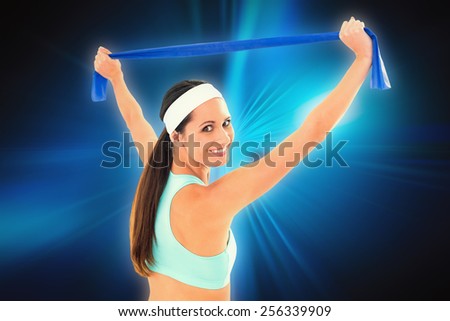 Fit young woman holding up a blue yoga belt against abstract background