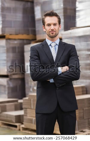 Serious male manager with arms crossed in a large warehouse